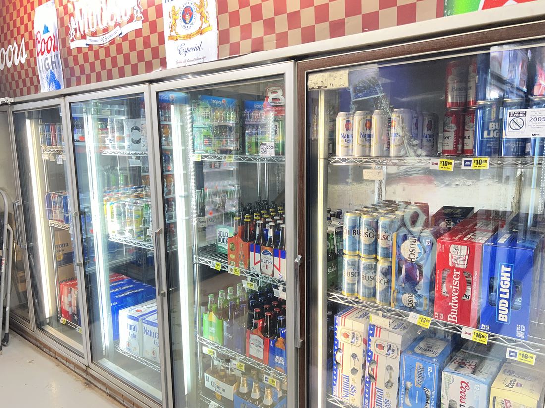 Inside the store — coolers stocked with beer, including Budweiser, Bud Light, Coors, Busch, Modelo, and Bold Rock Cider.